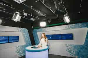 Free photo tv present at studio preparing for new broadcasting. smiling girl in white shirt sitting at table .