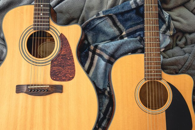 Two acoustic guitars on a cozy plaid top view