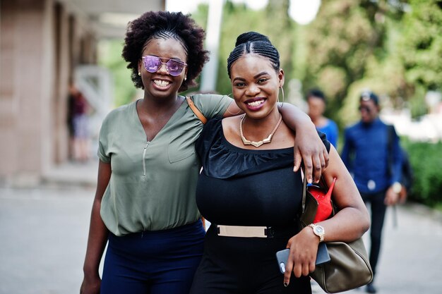 Two african american girls walking and posed at street of city