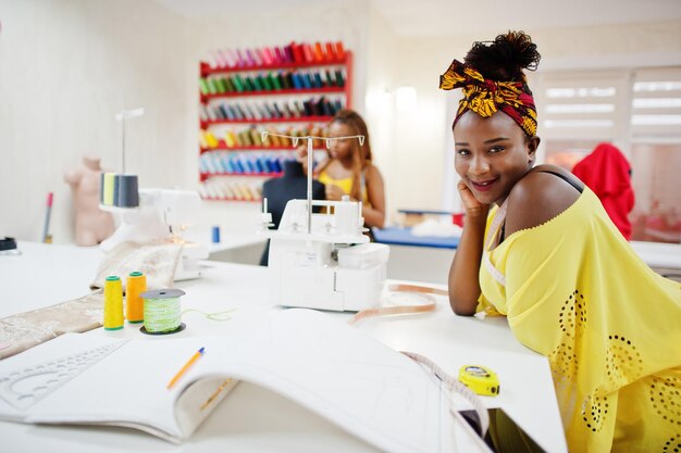 Two african dressmaker woman sews clothes on sewing machine at tailor office Black seamstress girls