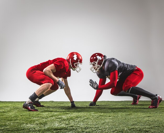 The two american football players in action on green grass and gray background.