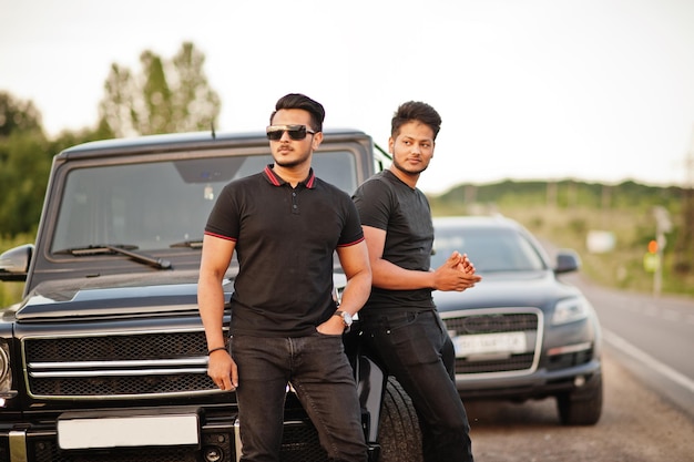 Free Photo two asian brothers man wear on all black posed near suv cars