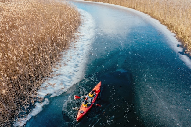 Free photo two athletic man floats on a red boat in river