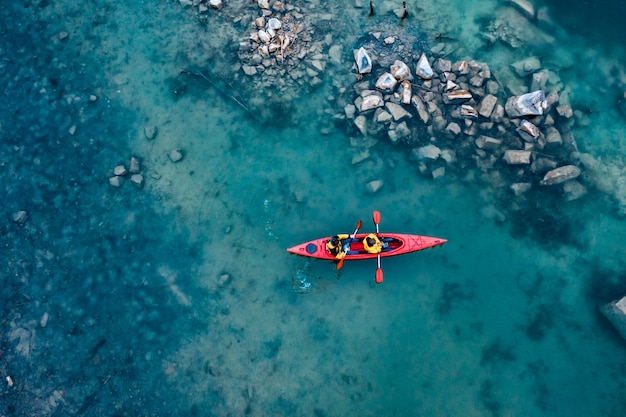 Free photo two athletic man floats on a red boat in river