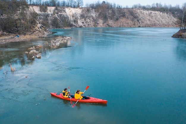 Free photo two athletic man floats on a red boat in river