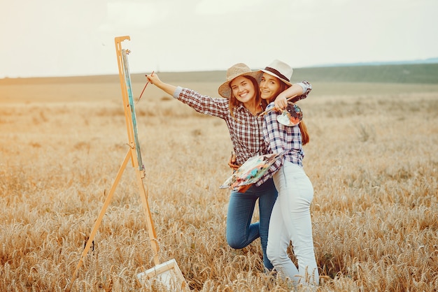 Two beautiful girls drawing in a field