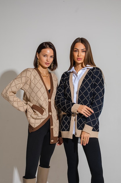 Two beautiful women posing to the camera in fashionable clothes