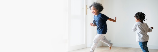 Free Photo two black kids playing and chasing each other in an empty room text space