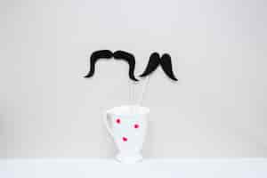 Free photo two black mustaches in cup with hearts