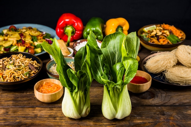 Two bokchoy in front of the thai delicious food on desk