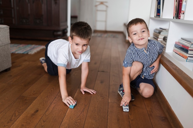 Free photo two boys playing with car toys on hardwood floor