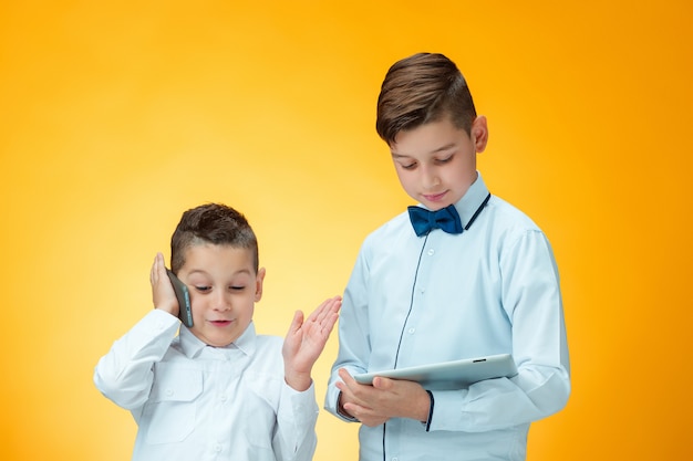 The two boys using laptop on orange wall