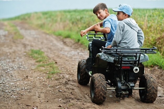 Two brothers driving fourwheller ATV quad bike Happy children moments