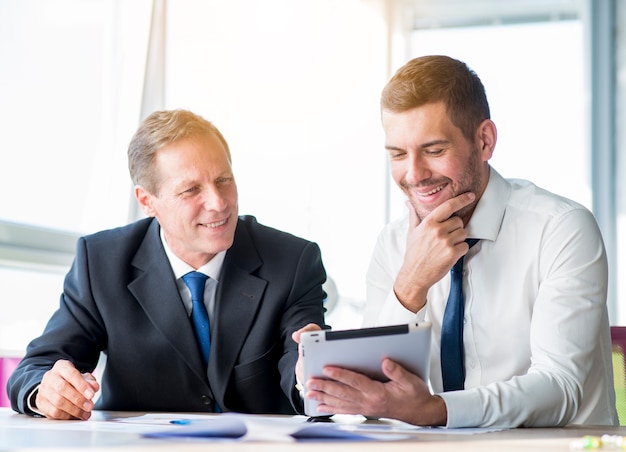 Free photo two businessman discussing using digital tablet