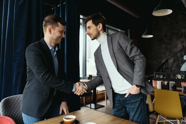 Free photo two businessmen shaking hands while meeting in lobby