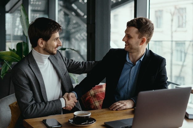 Free Photo two businessmen shaking hands while meeting in lobby