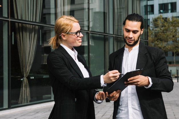 Free Photo two businesspeople discussing business project over clipboard at outdoors