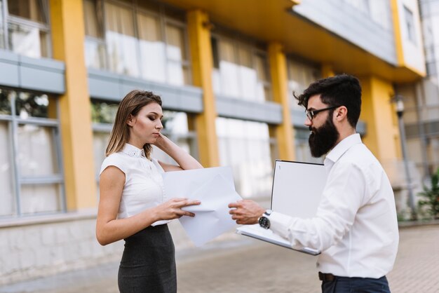 Two businesspeople looking at document standing outside the office