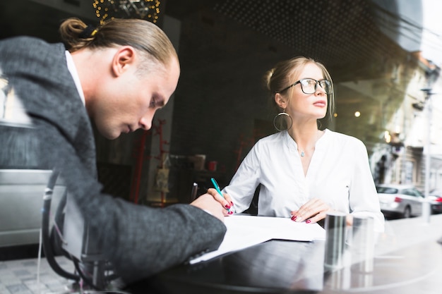 Free Photo two businesspeople working on document in restaurant