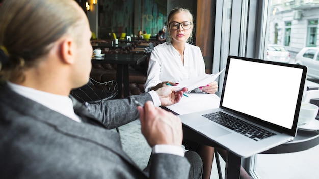 Two businesspeople working on document with laptop on desk