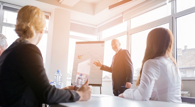 Two businesswoman looking at businessman giving presentation