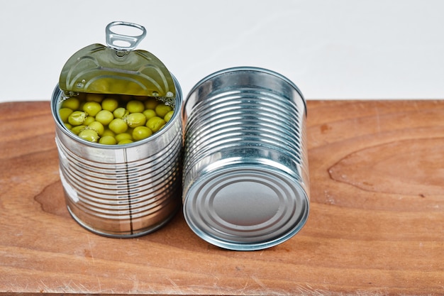 Free photo two cans of boiled green peas on a wooden board.