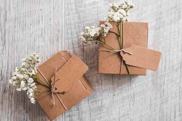 Two cardboard boxes with tag and baby's-breath flowers on wooden backdrop