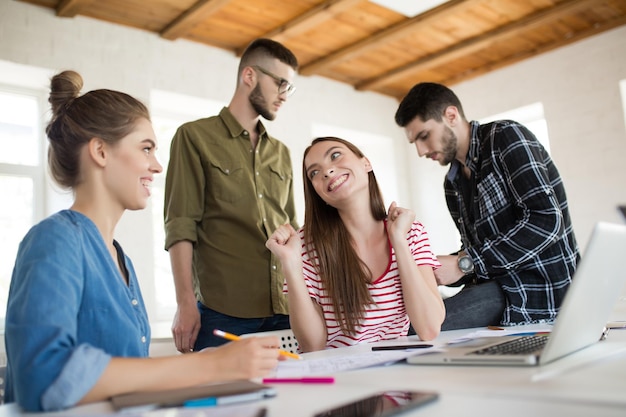 Free Photo two cheerful girls joyfully talking while spending time in modern office with colleagues on background group of creative people working together