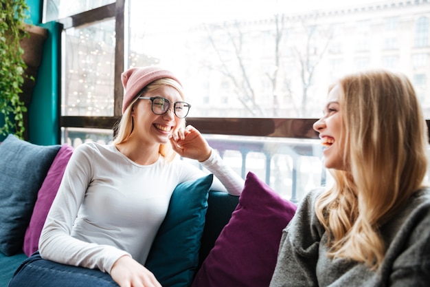 Free photo two cheerful women talking and laughing in cafe