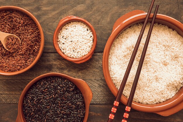 Two chopsticks on rice bowls over wooden table