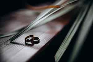 Free photo two classy golden rings lie under green leaves on a wooden table