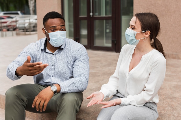 Two colleagues chatting outdoors during pandemic with masks