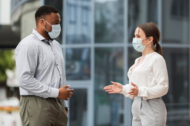 Two colleagues chatting outdoors during pandemic with masks