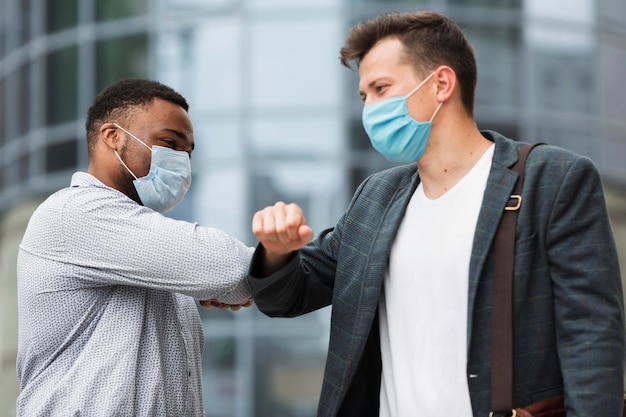 Two colleagues touching elbows outdoors during pandemic