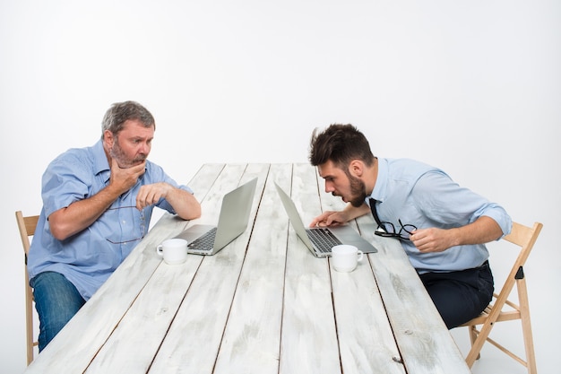 Free Photo the two colleagues working together at office on white  background. both are looking at the computer screens. both very upset. concept of negative emotions and bad news