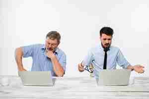 Free photo the two colleagues working together at office on white  background. both are looking at the computer screens.  concept of negative emotions and bad news