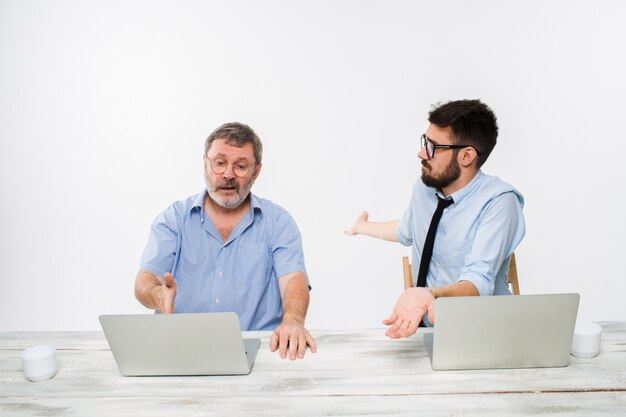 The two colleagues working together at office on white wall