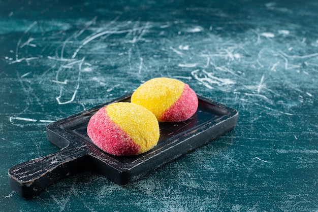 Free photo two colored cookies on black cutting board.