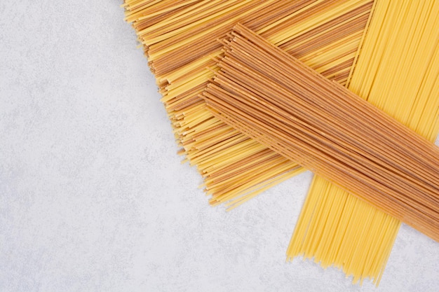 Free photo two colors of raw spaghetti pasta on white table.