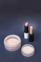 Free photo two container of beige blusher powder and lipsticks on gray backdrop