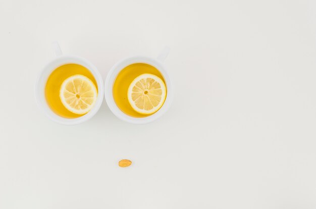 Two cup of ginger tea with lemon slice isolated on white backdrop