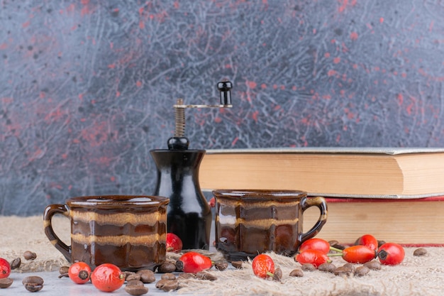 Free Photo two cups of coffee with beans and rosehips on table. high quality photo