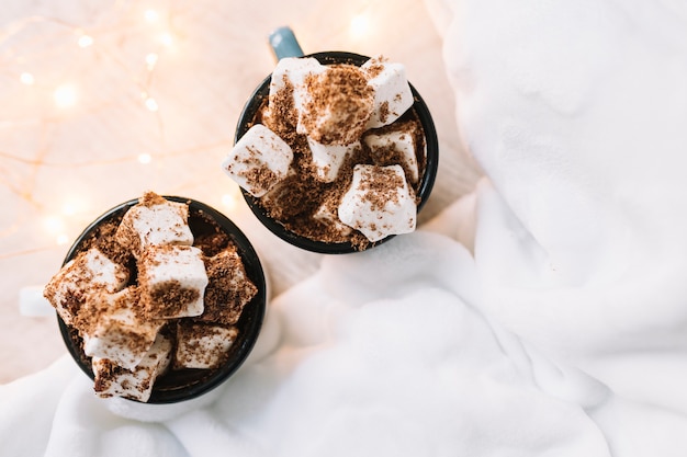 Free Photo two cups with marshmallows and cocoa powder on table