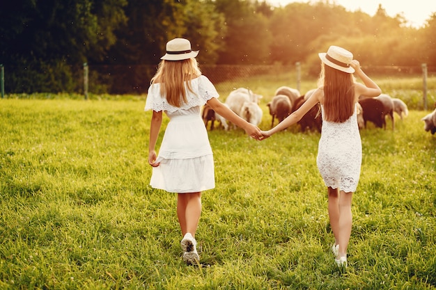 Free photo two cute girls in a field with a goats