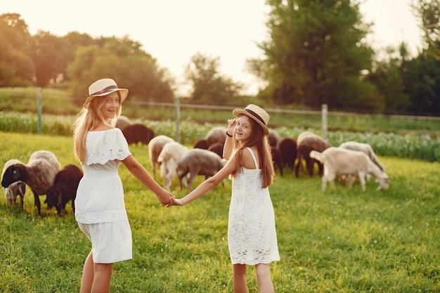 Free Photo two cute girls in a field with a goats