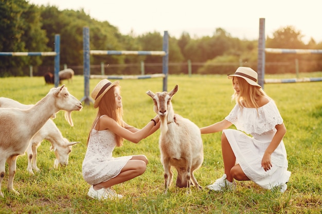 Free Photo two cute girls in a field with a goats