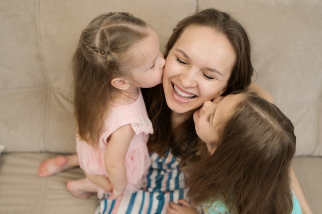 Two daughters kissing their mommy