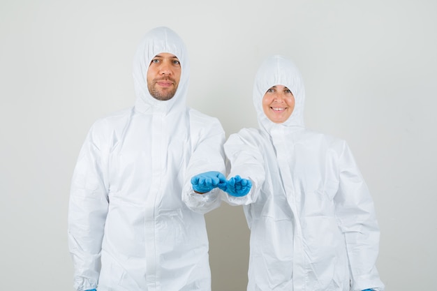 Two doctors stretching out palms in protective suit