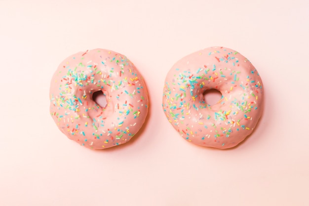 Two donuts with colorful sprinkles arranged on background