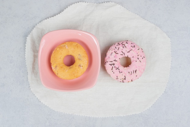 Two donuts with sprinklers on marble table. High quality photo